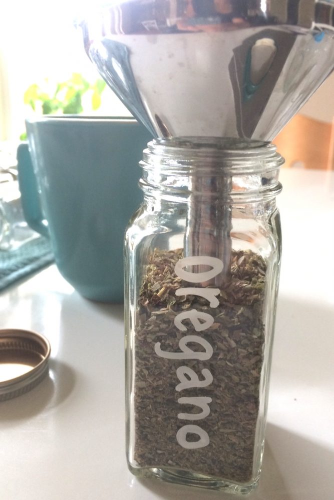 A close up oregano spice bottle being filled with oregano