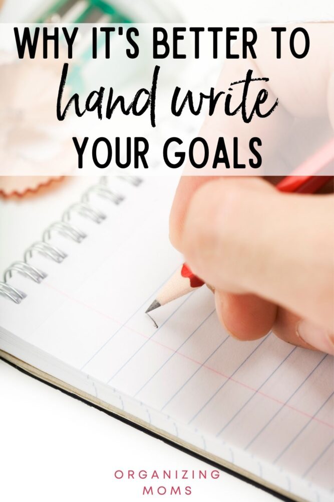 text why it's better to handwrite your goals. image of person writing in notebook with a red pencil