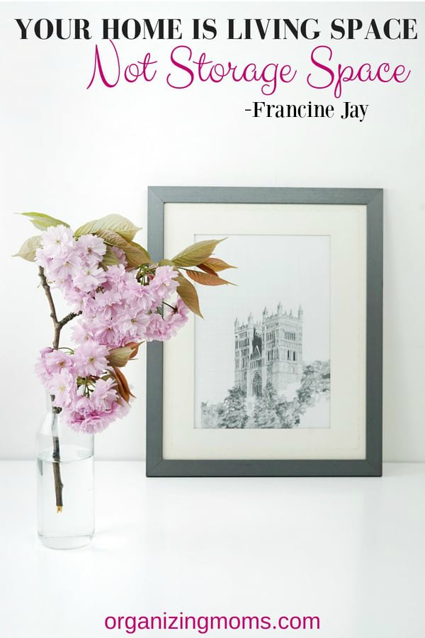 A vase of flowers on a table. Picture of castle. Text - Your home is living space, not storage space - Francine Jay.