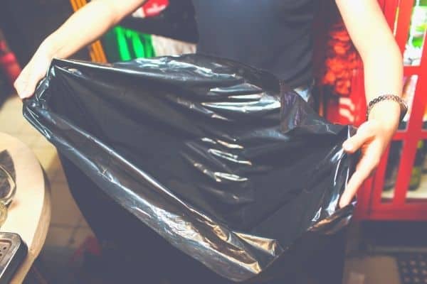 woman holding black trash bag open