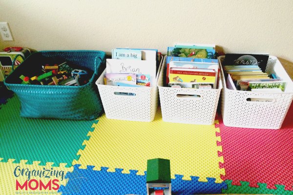 children\'s books organized in baskets on colorful floor