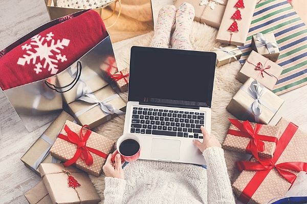 shopping for christmas on laptop surrounded by gifts