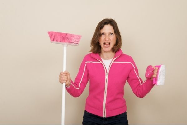 Woman who has cleaning motivation, carrying a pink broom and cleaning brush.