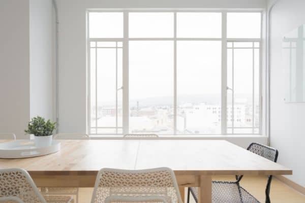 clear kitchen table in front of bright window tray and plant on table white walls