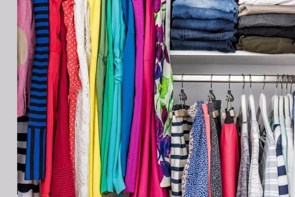 colorful clothes hanging in closet, folded jeans