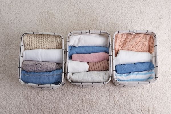 three fabric baskets with clothes inside on floor