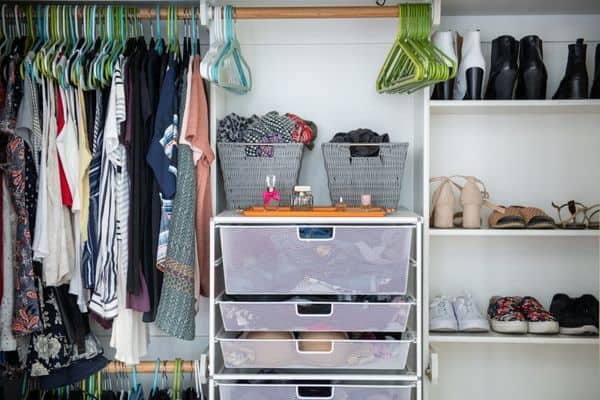 closet with hanging clothes, baskets, bins, drawers and shoes.