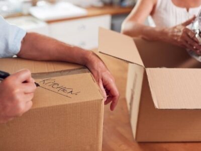 two boxes being filled with kitchen items to symbolize decluttering and downsizing