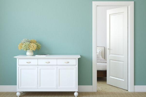 decluttered and organized white dresser and door with blue wall