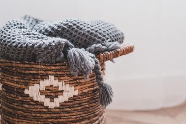 Gray blanket in brown wicker basket on floor