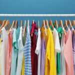 colorful clothes hanging on a rack with blue background. rack set up for decluttering clothes