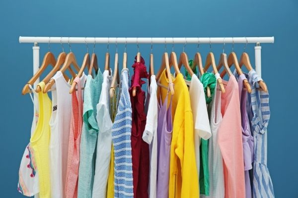 colorful clothes hanging on a rack with blue background. rack set up for decluttering clothes