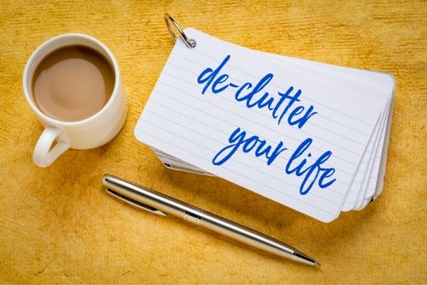 Declutter your life text on a notecard, next to pen and cup of coffee