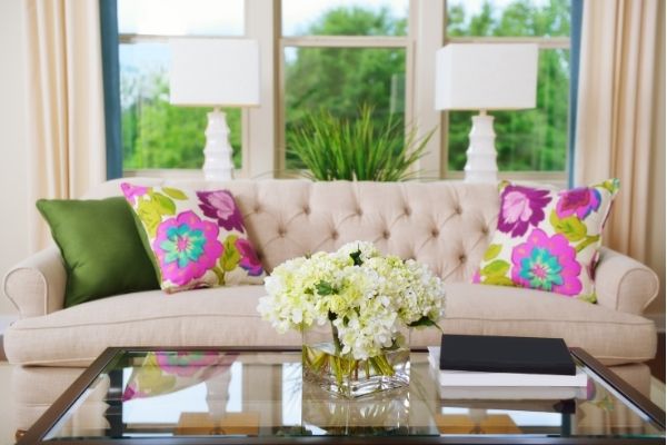 decluttered table with hydrangeas sofa with colorful pillows in front of window