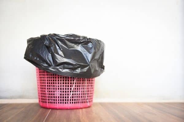 pink garbage can with black bag on wooden floor