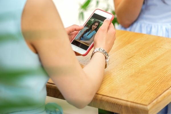 woman looking at digital photo on phone while sitting at table