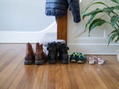 shoes on floor in front of stairs with plant coat hanging from stairway