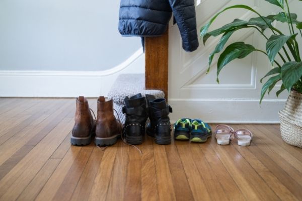 shoes on floor in front of stairs with plant coat hanging from stairway