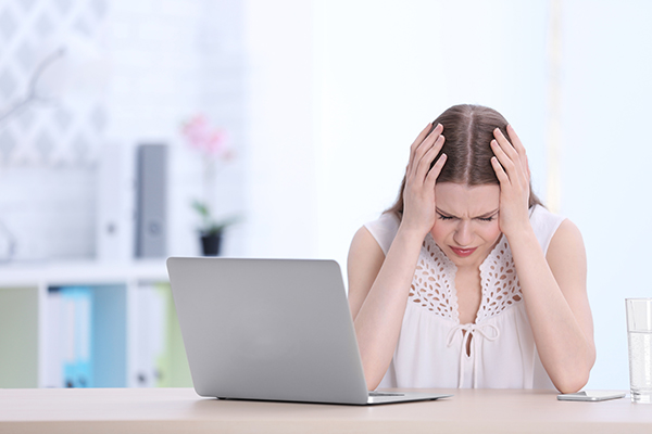 A woman looking overwhelmed next to a laptop