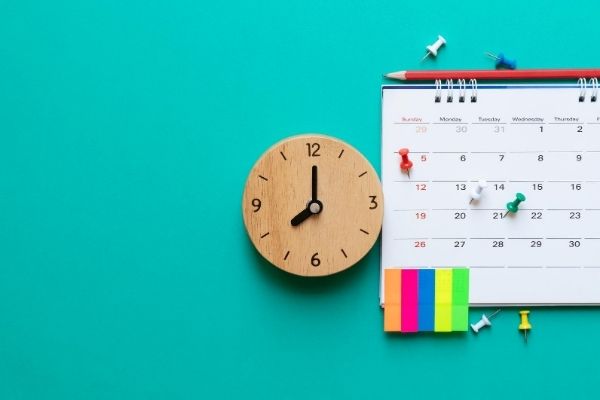 Clock, calendar, office supplies on blue background.