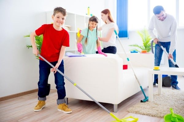 A family cleaning a room with mops and dusters