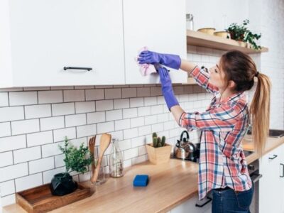 Woman cleaning cabinets in kitchen