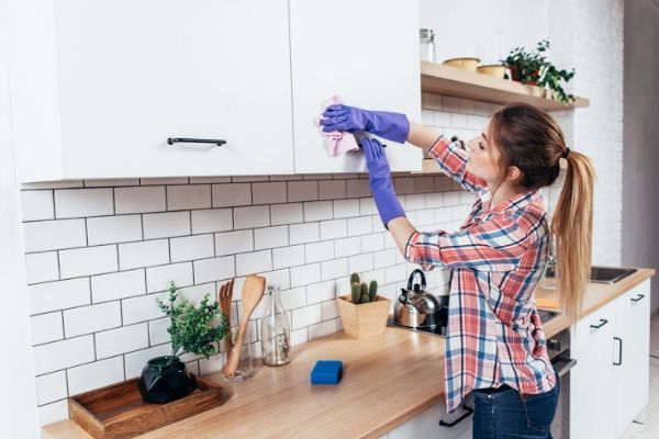 Woman cleaning cabinets in kitchen