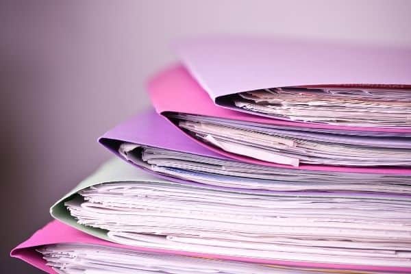 pink and purple file folders full of paper that need a filing system declutter