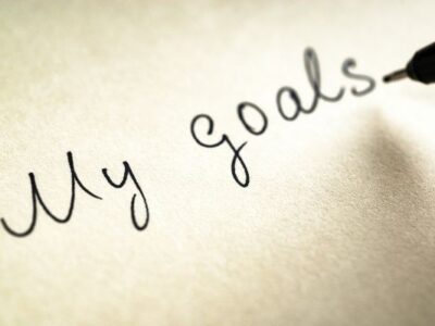 black pen writing out "my goals" on paper to symbolize handwritten goals