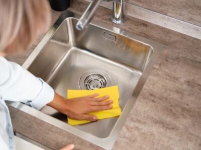 woman wiping sink with yellow cloth to symbolize household habits