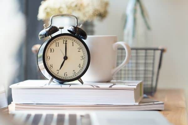 black clock on top of book by mug