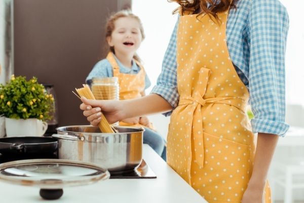 A woman and child cooking spaghetti