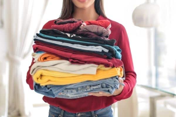 woman holding clean laundry to put in suitcases