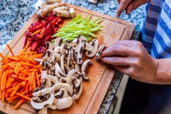 person chopping vegetables on cutting board for meal prep organization