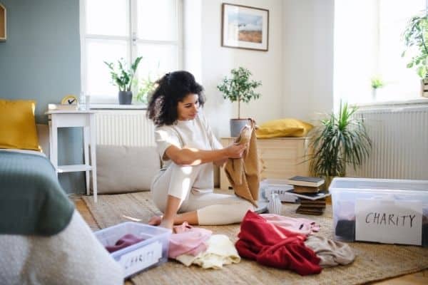woman doing month of decluttering putting clothes in piles