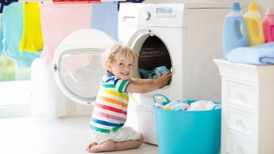 Child putting clothing into a dryer for chores