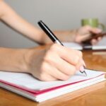 woman writing in spiral notebook to symbolize organize your ideas with notebooks concept