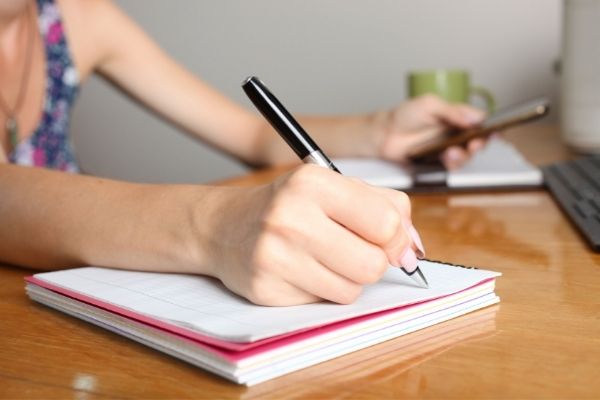 woman writing in spiral notebook to symbolize organize your ideas with notebooks concept