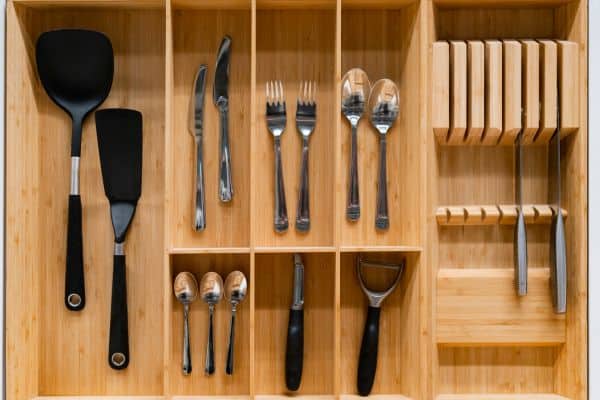 organized kitchen drawer with knife block, silverware, black spatulas