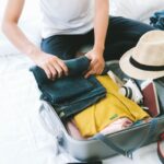 Woman preparing for organized travel rolling clothes before putting them in suitcase.