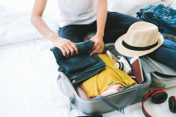 Woman preparing for organized travel rolling clothes before putting them in suitcase.