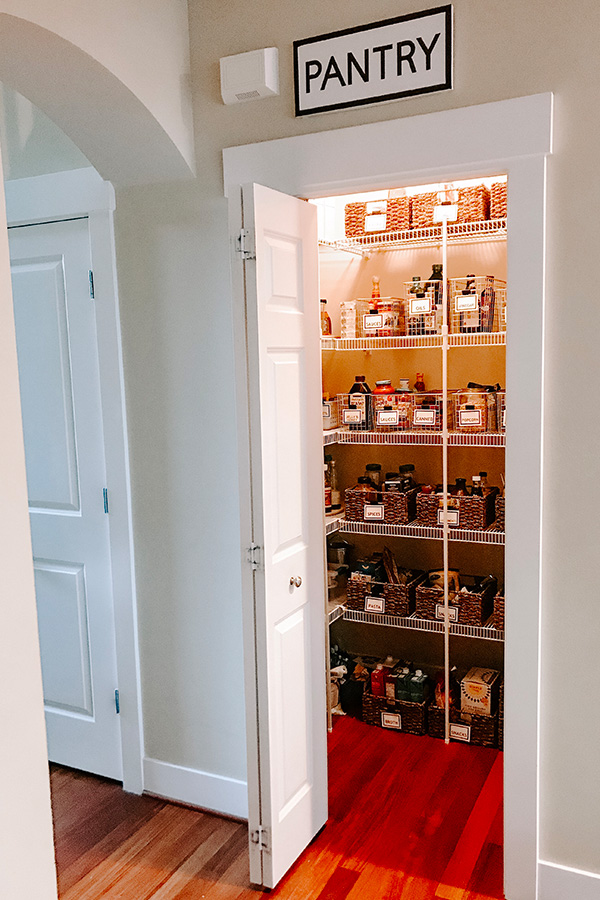 Pantry organized with baskets as seen from a distance. Pantry door open.