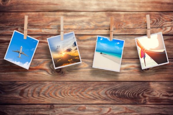 Colorful photographs pinned to clothesline with wood background