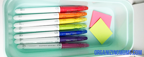 Colorful markers and sticky notes in blue container