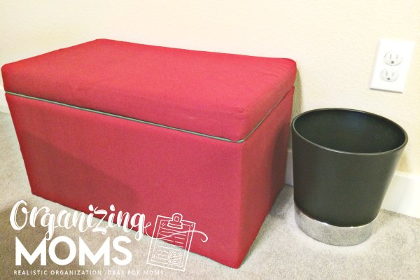 red fabric toy storage box that can also be a bench next to a black trash can