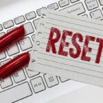 lined paper with the word reset printed in red marker on top of keyboard with two red markers to the left to symbolize reset week after christmas