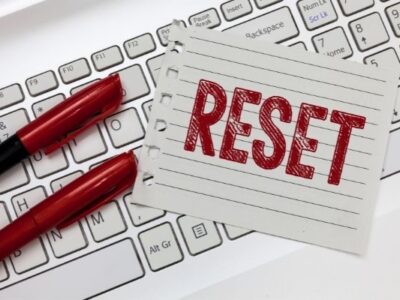 lined paper with the word reset printed in red marker on top of keyboard with two red markers to the left to symbolize reset week after christmas