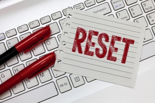 lined paper with the word reset printed in red marker on top of keyboard with two red markers to the left to symbolize reset week after christmas