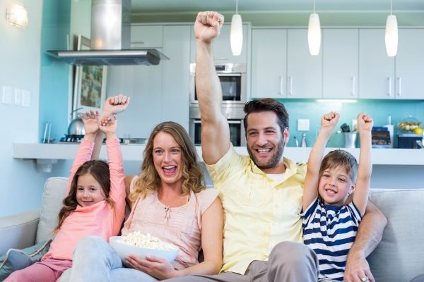 Family eating popcorn and cheering during screen time