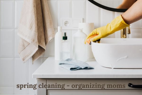 image of person cleaning a sink, wearing yellow glove